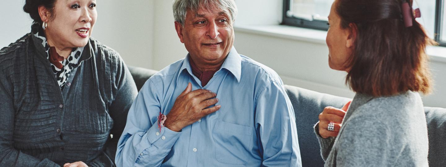 A young woman sits with an elderly couple having a conversation